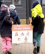 Kita-Kinder tragen die Blühkiste auf das Geländer ihrer Kita